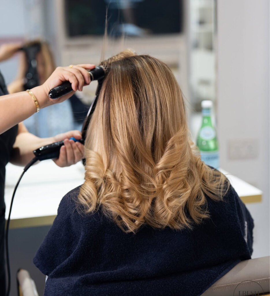Blow-dry and curling of long blonde hair at Fresh & Go Beauty Bar in Al Messila, Doha