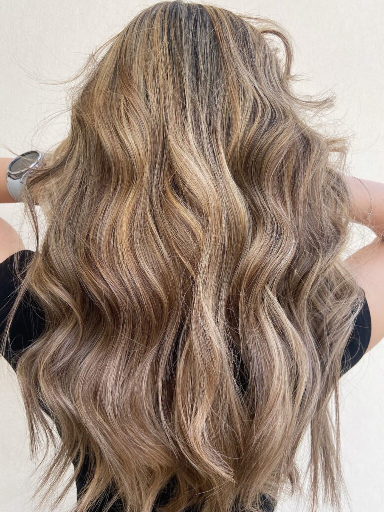 Long hair with blonde balayage and soft waves styled at Kensington Hair & Beauty in Al Luqta, Doha