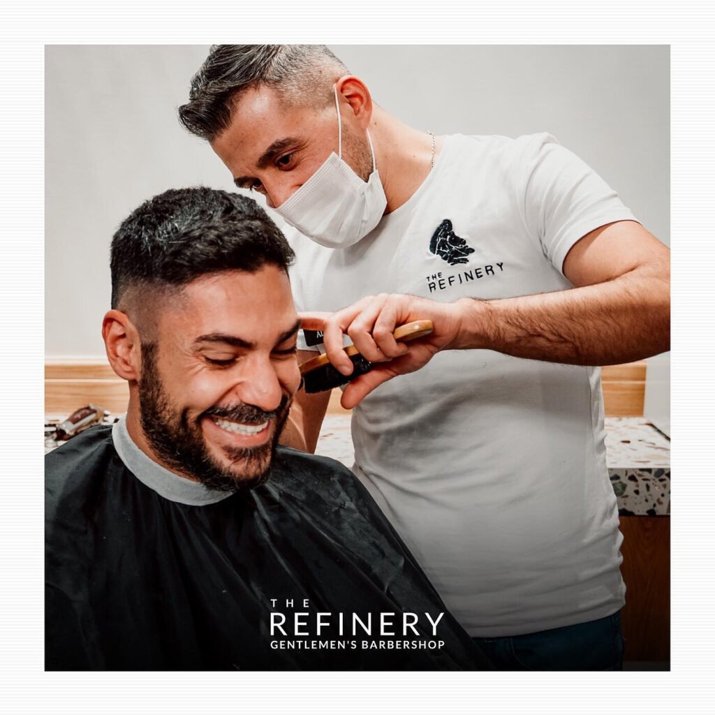 Barber finishing a fade with a trimmer at The Refinery Gentlemen's Barbershop on The Pearl, Doha